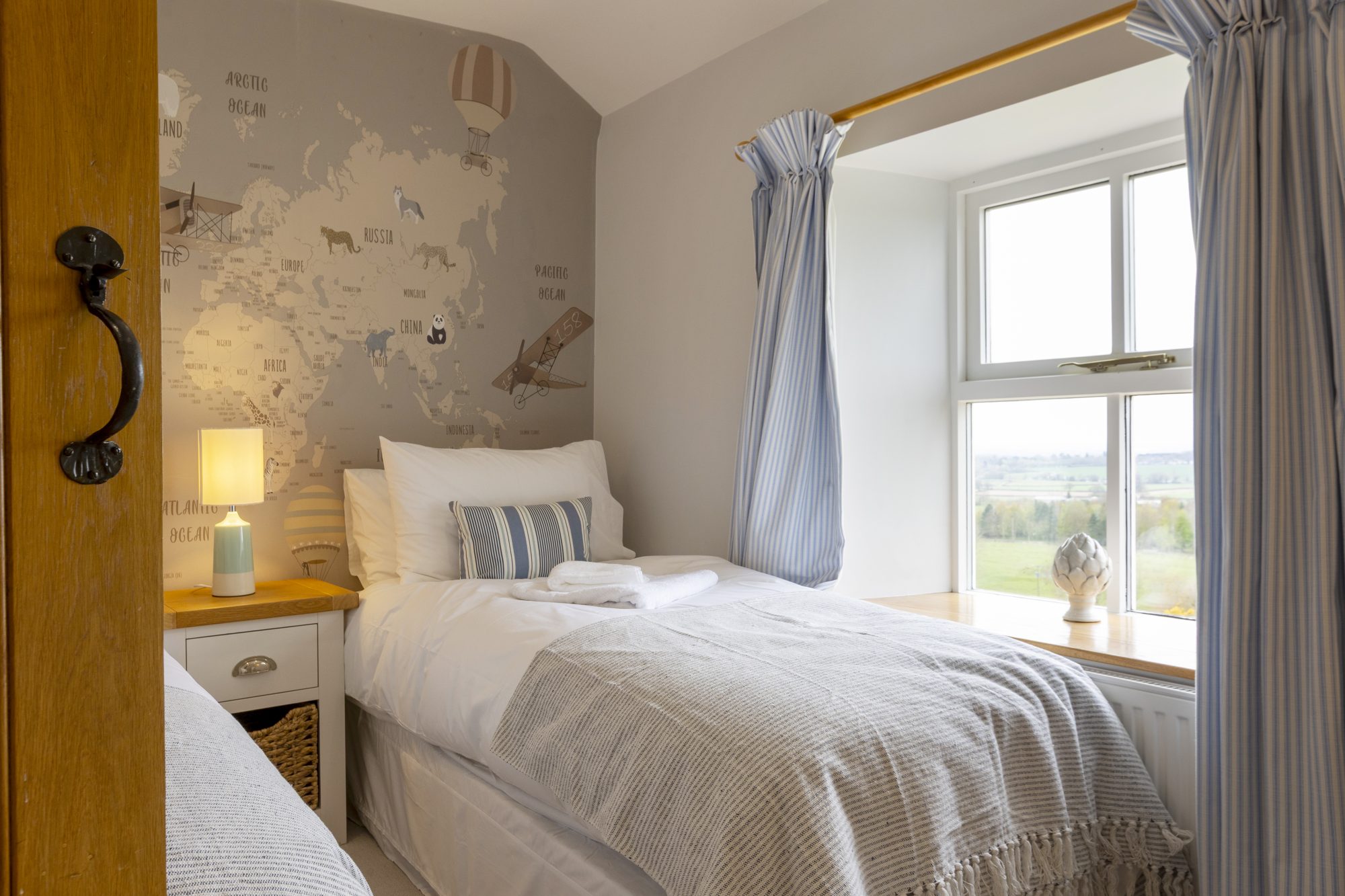 Single bedroom with map wallpaper and countryside view