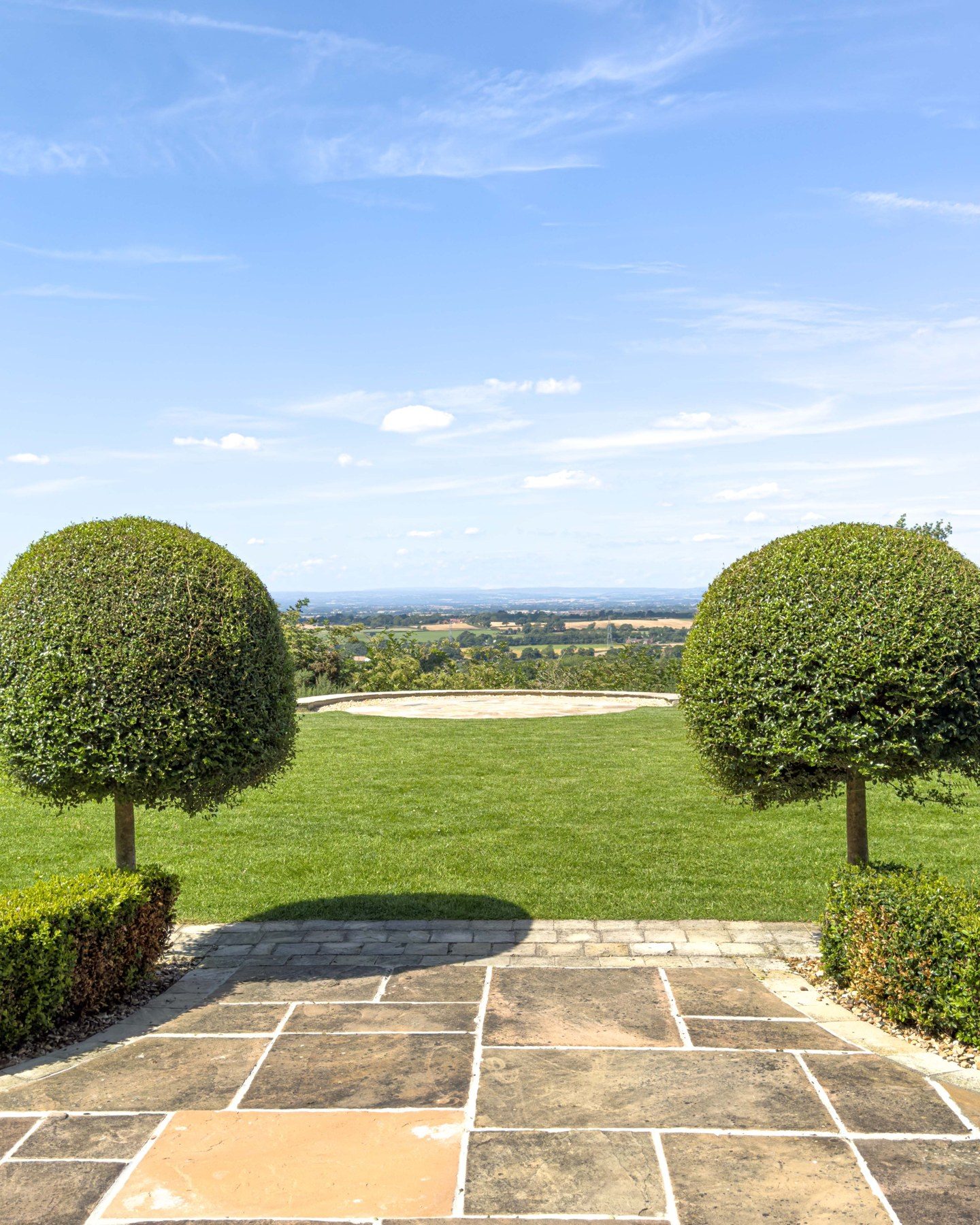 Stone patio with clipped trees and open view