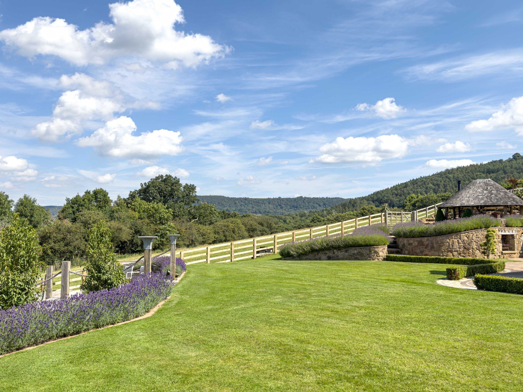 Wrap-around lawn with paddock fencing and hills beyond