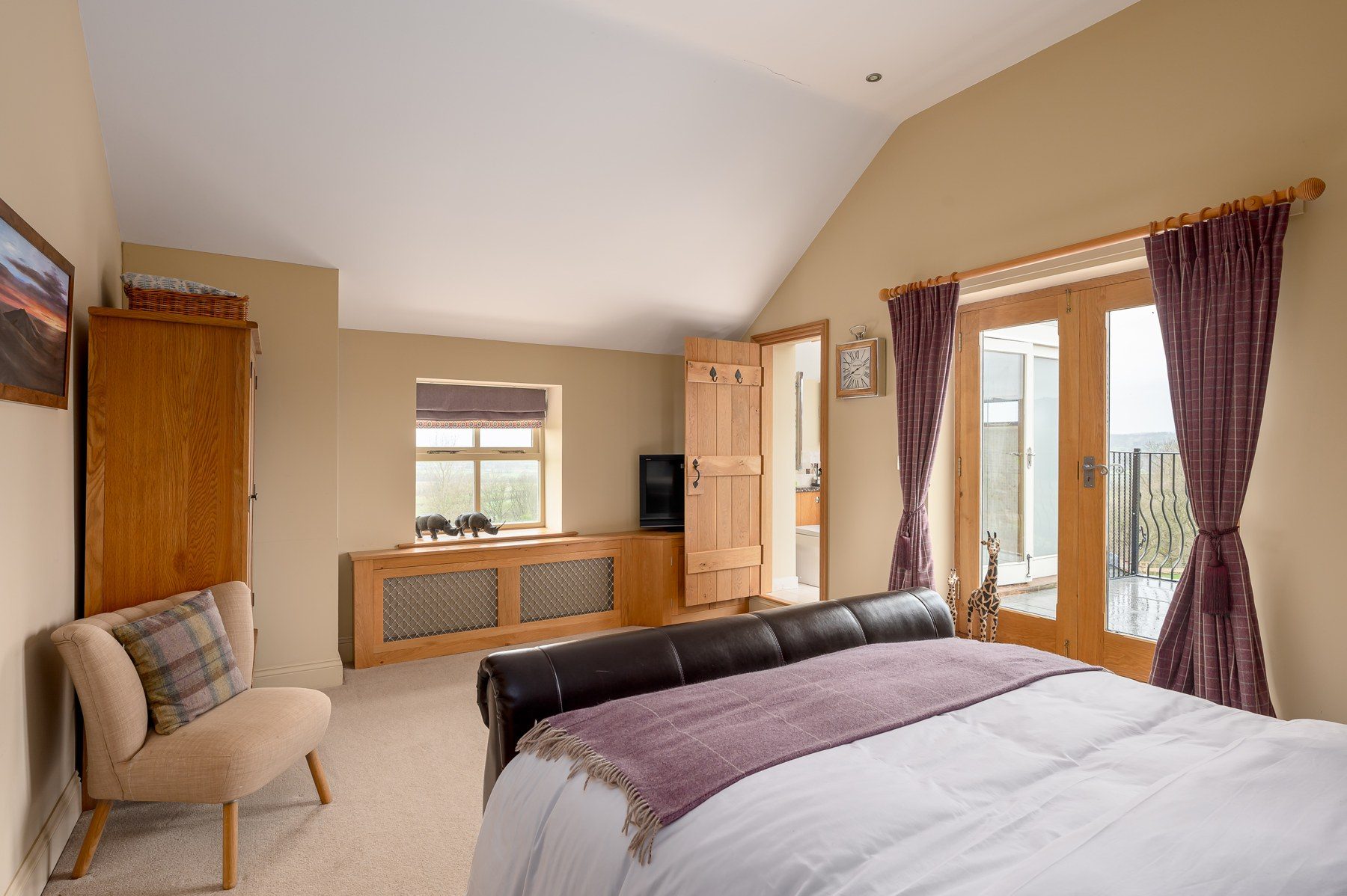 Bedroom 2 with leather sleigh bed and French doors to the balcony