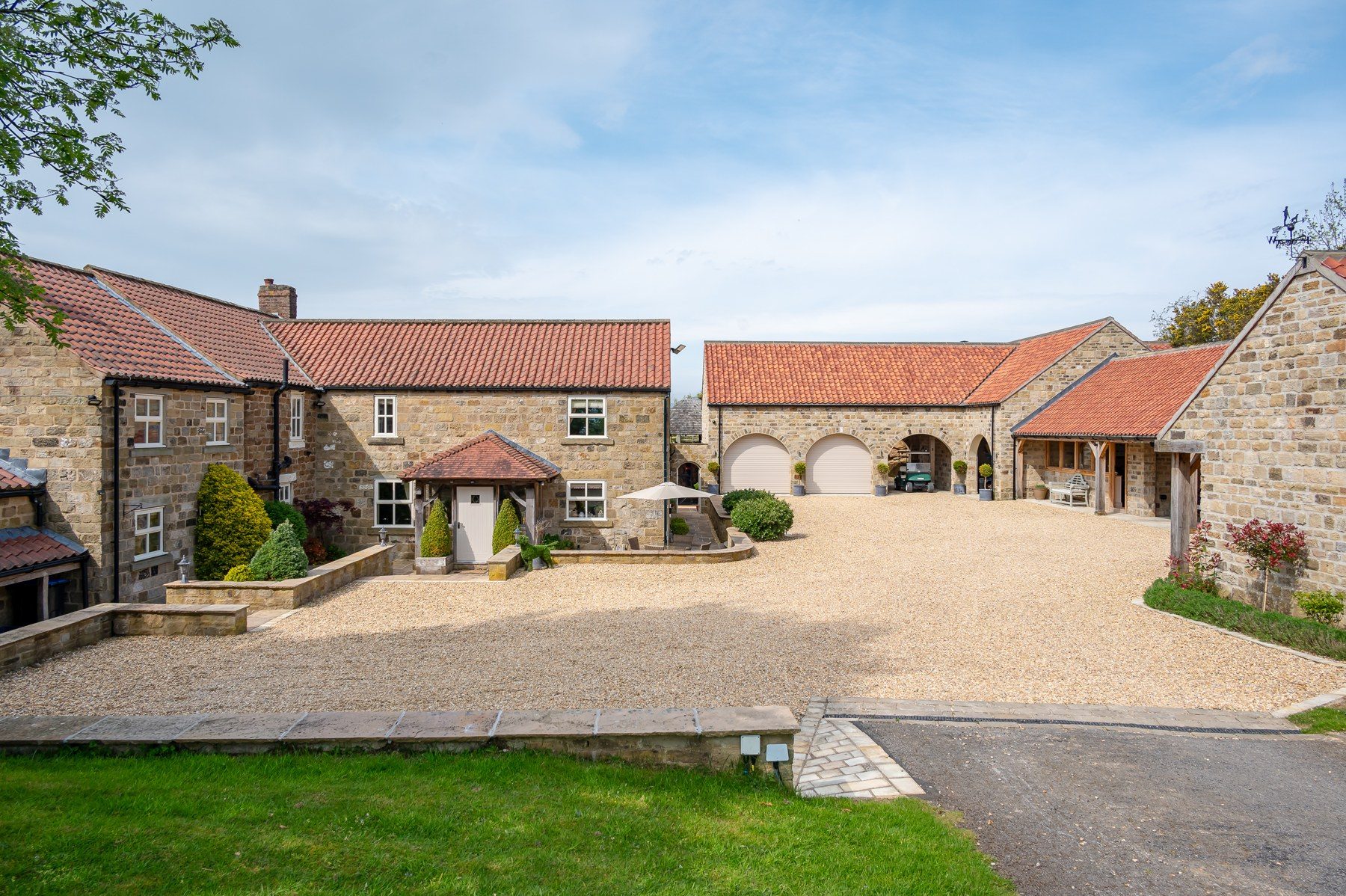 Gravel courtyard with arched garaging and parking
