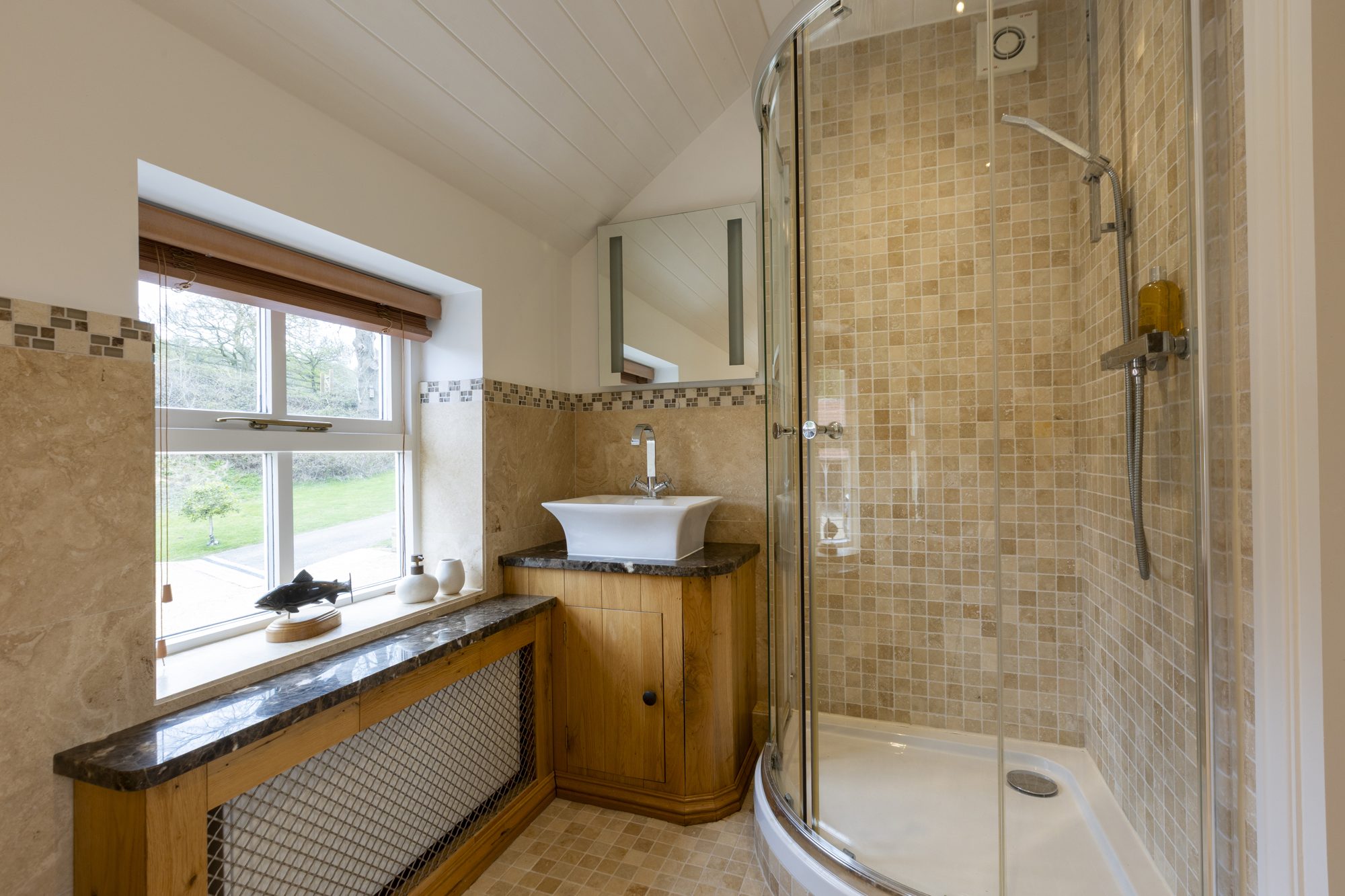 Walk-in shower with oak vanity and leafy outlook