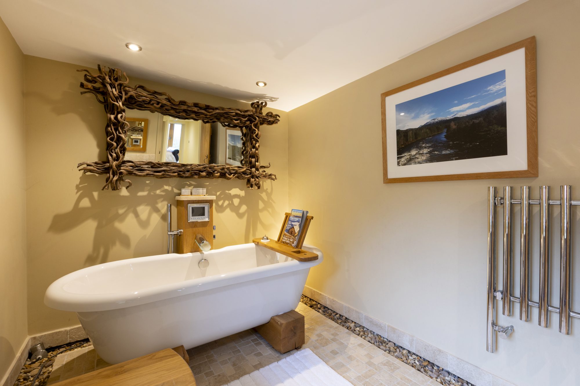 Freestanding bath beneath an ornate driftwood mirror